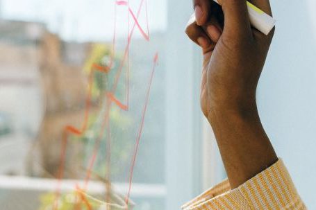 Trading Strategies - A Person Writing on a Glass Panel Using a Whiteboard Marker